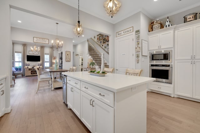 kitchen with light wood finished floors, hanging light fixtures, a notable chandelier, white cabinets, and stainless steel appliances