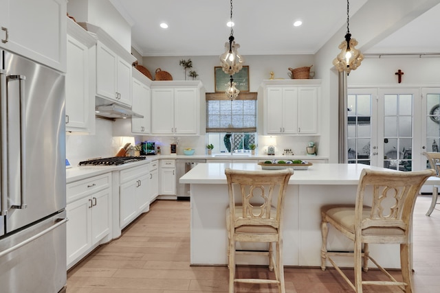 kitchen featuring under cabinet range hood, light countertops, appliances with stainless steel finishes, and a kitchen island