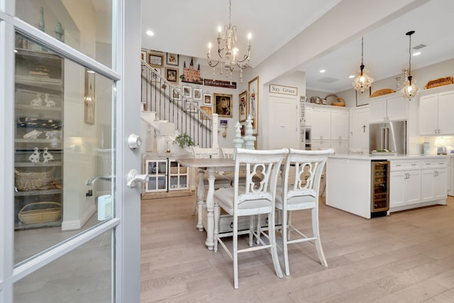 dining area with stairway, wine cooler, a notable chandelier, and light wood-style floors