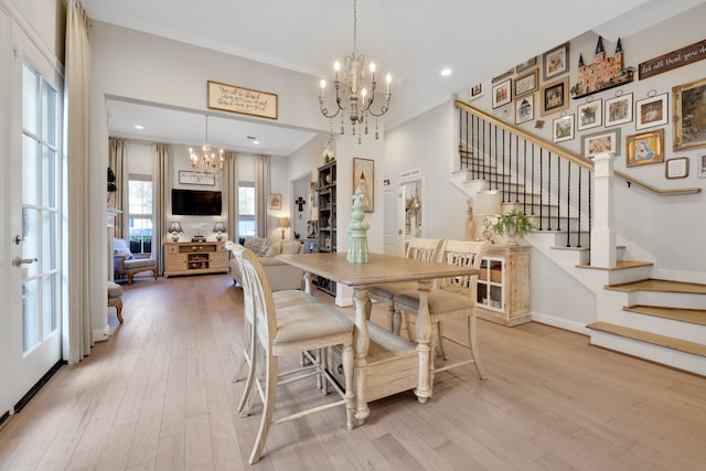 dining space with light wood-type flooring, a notable chandelier, crown molding, baseboards, and stairs