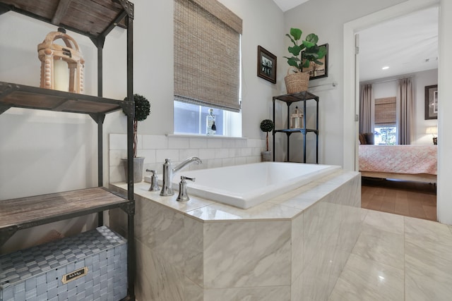 ensuite bathroom with tile patterned flooring, ensuite bath, plenty of natural light, and a bath