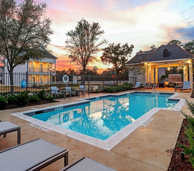 pool at dusk featuring a patio area, a community pool, and fence