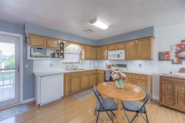 kitchen featuring white appliances, light countertops, visible vents, and a sink