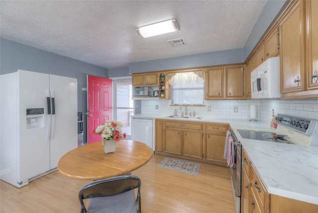 kitchen with visible vents, light countertops, light wood-style floors, white appliances, and a sink