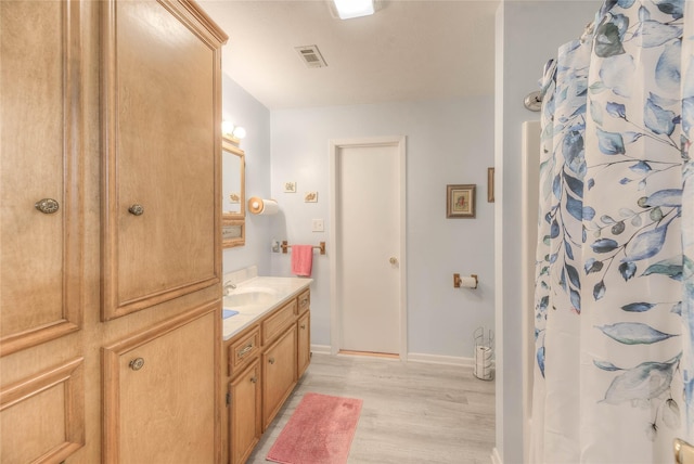 full bath featuring visible vents, a shower with curtain, wood finished floors, baseboards, and vanity