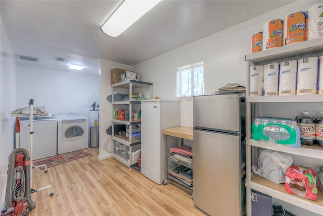 washroom with light wood finished floors, visible vents, crown molding, and separate washer and dryer