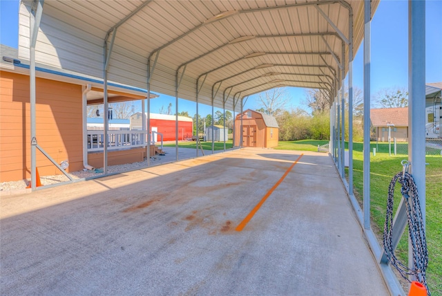 view of parking / parking lot featuring a detached carport, a storage shed, and fence