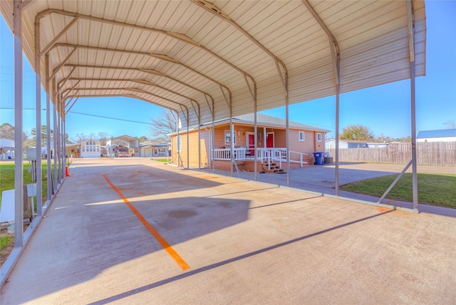 view of property's community with a detached carport, concrete driveway, fence, and a residential view