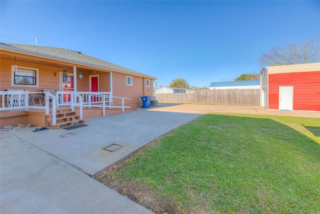 view of yard with a patio, fence, and an outbuilding