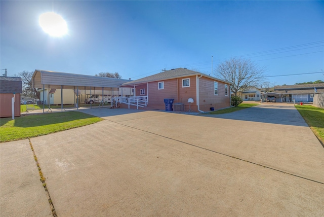 exterior space with a detached carport, a lawn, concrete driveway, and central AC