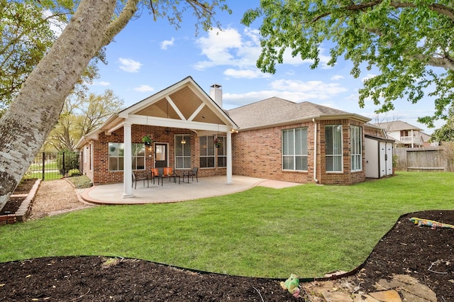 back of house with a patio area, brick siding, a chimney, and fence