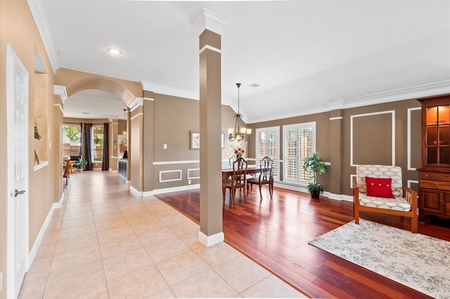 foyer entrance featuring decorative columns, arched walkways, and ornamental molding