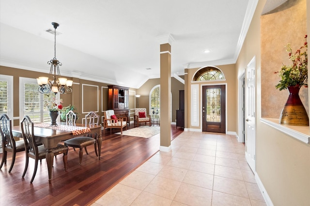 foyer entrance with a wealth of natural light, visible vents, an inviting chandelier, and crown molding