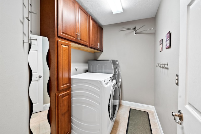 laundry room featuring washing machine and clothes dryer, baseboards, light tile patterned flooring, cabinet space, and a textured ceiling