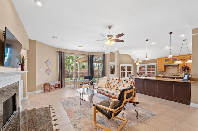 living area with visible vents, ceiling fan, vaulted ceiling, a fireplace, and light tile patterned flooring