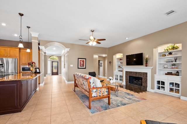 living area featuring arched walkways, built in features, visible vents, and light tile patterned floors