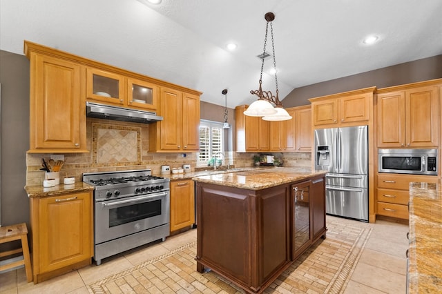 kitchen with hanging light fixtures, vaulted ceiling, glass insert cabinets, under cabinet range hood, and appliances with stainless steel finishes