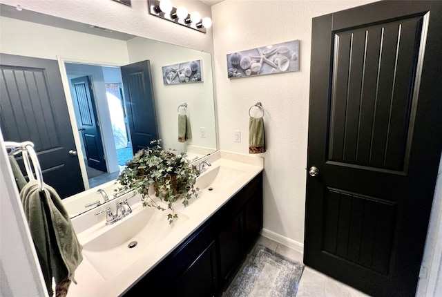 bathroom with double vanity, baseboards, visible vents, and a sink