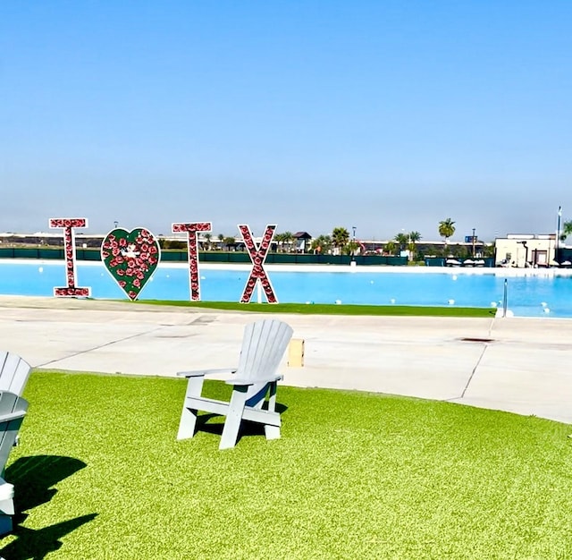 view of pool with a yard and a water view