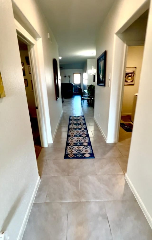 corridor with light tile patterned flooring and baseboards