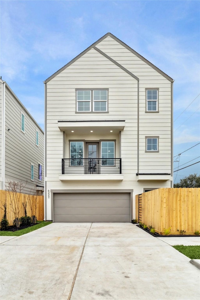 view of front of property with driveway, an attached garage, a balcony, and fence