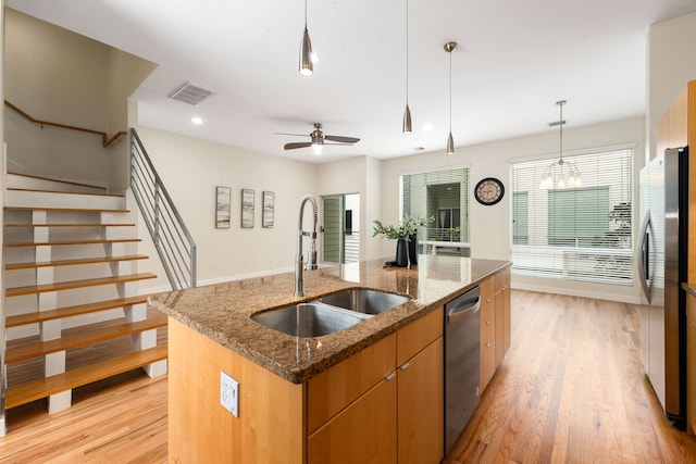 kitchen with light wood finished floors, visible vents, an island with sink, stainless steel appliances, and a sink