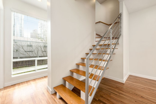 staircase with baseboards, plenty of natural light, and wood finished floors