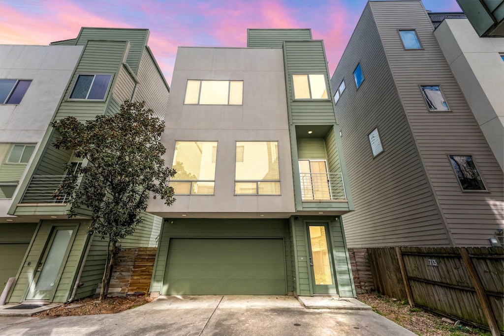 713 Andrews St, Houston, TX 77019 - back of property with a balcony, fence, concrete driveway, a garage, and stone siding