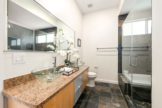 full bathroom featuring a shower with shower door, visible vents, toilet, stone tile flooring, and baseboards