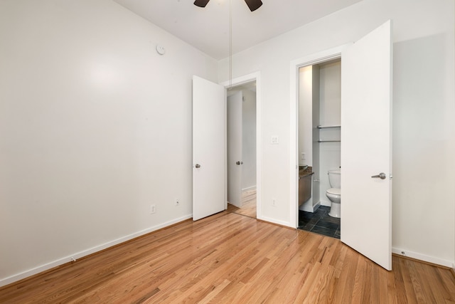 unfurnished bedroom featuring baseboards, a ceiling fan, wood finished floors, and ensuite bathroom