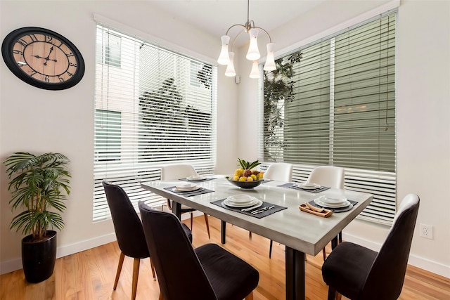 dining space featuring baseboards, light wood-style floors, and an inviting chandelier