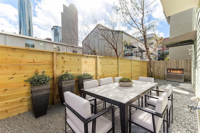 view of patio with outdoor dining space, a city view, and fence