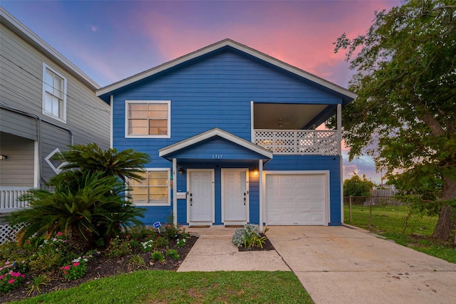 view of front of house with an attached garage, driveway, a balcony, and fence