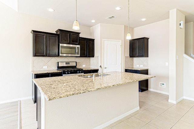 kitchen featuring visible vents, appliances with stainless steel finishes, light stone countertops, and a sink