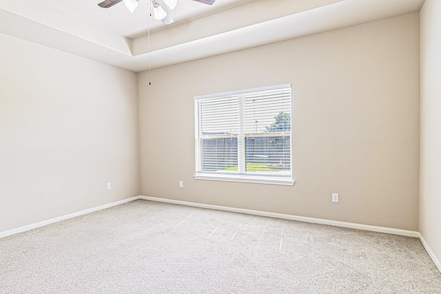 unfurnished room featuring light carpet, baseboards, a raised ceiling, and ceiling fan