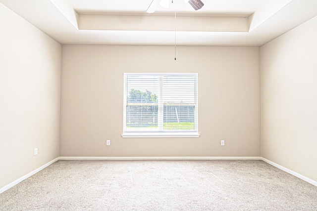 spare room featuring baseboards, a raised ceiling, carpet floors, and a ceiling fan