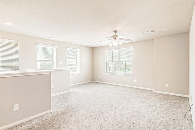 unfurnished room featuring visible vents, light carpet, baseboards, and ceiling fan