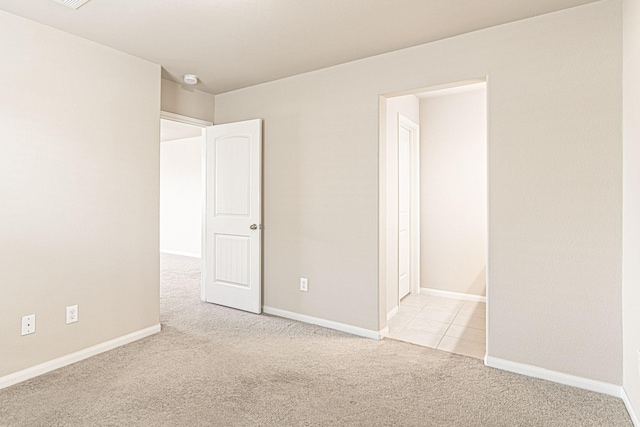 unfurnished room featuring baseboards and light carpet