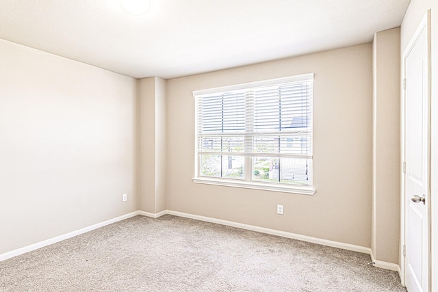 empty room featuring carpet and baseboards