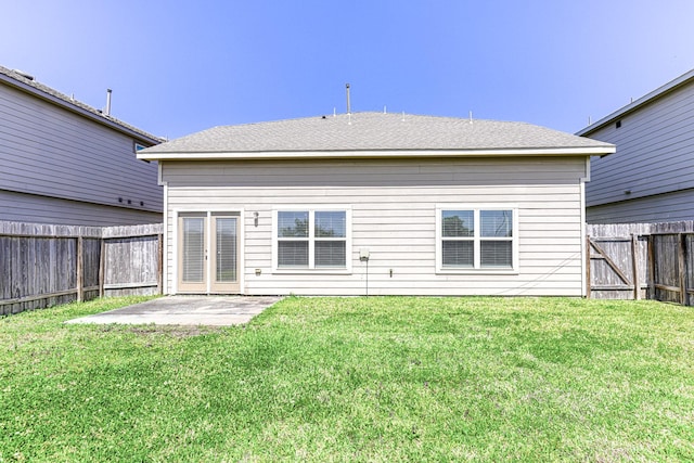 rear view of house with a patio area, a lawn, a fenced backyard, and a shingled roof