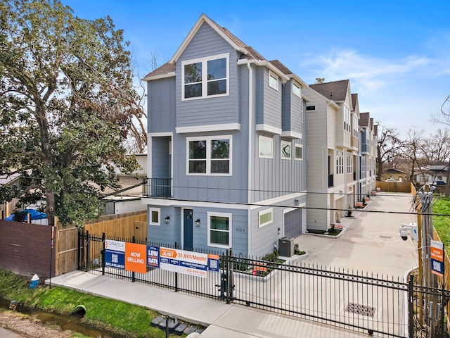 view of front of house with fence, a residential view, and central AC