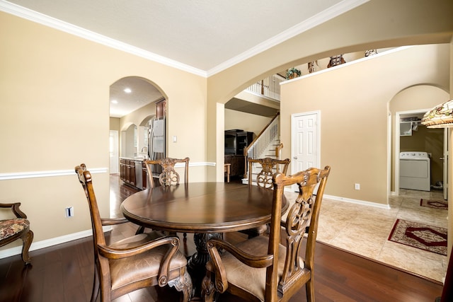 dining area featuring stairway, arched walkways, washer / dryer, and wood finished floors