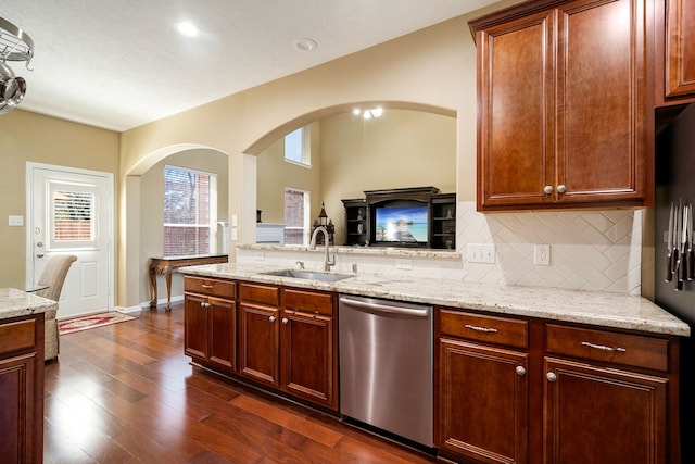 kitchen featuring a sink, backsplash, dark wood-style floors, stainless steel appliances, and light stone countertops