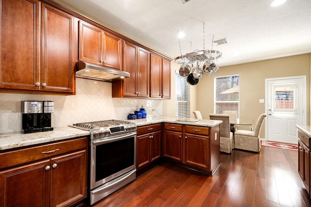 kitchen featuring stainless steel gas range oven, dark wood-type flooring, under cabinet range hood, a peninsula, and decorative backsplash