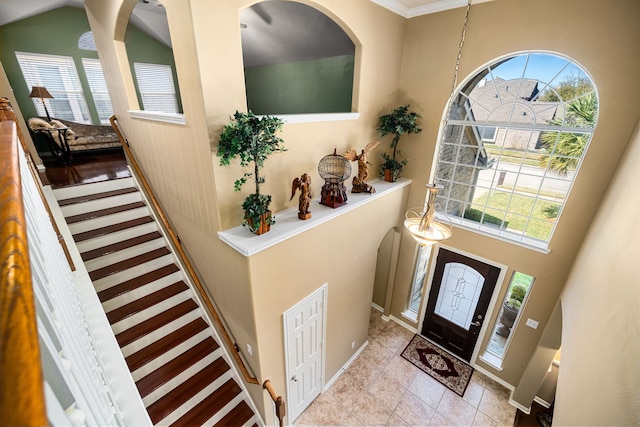 foyer entrance with arched walkways, plenty of natural light, stairs, and a towering ceiling