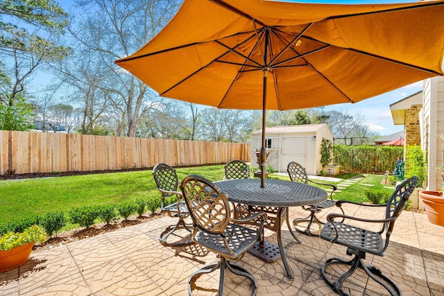 view of patio / terrace featuring a storage shed, an outbuilding, outdoor dining area, and a fenced backyard