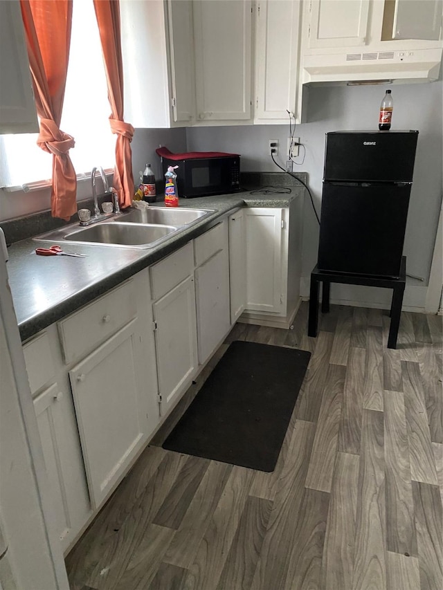 kitchen with a sink, light wood-type flooring, black appliances, and white cabinetry