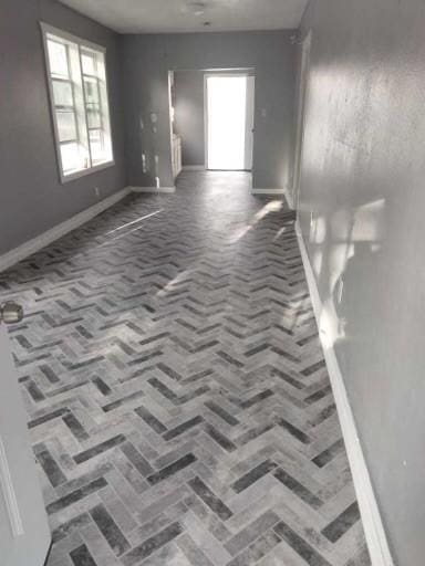 empty room with baseboards and brick floor