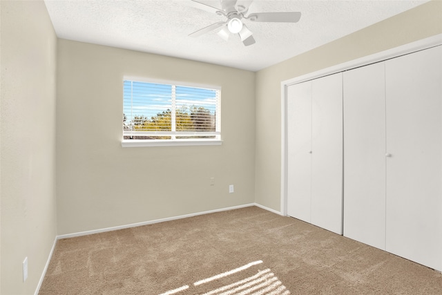 unfurnished bedroom featuring baseboards, ceiling fan, carpet, a closet, and a textured ceiling