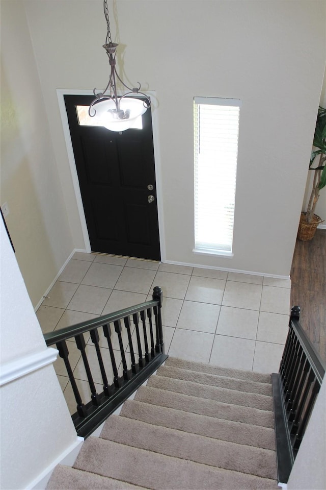 foyer with baseboards, light tile patterned flooring, and stairs